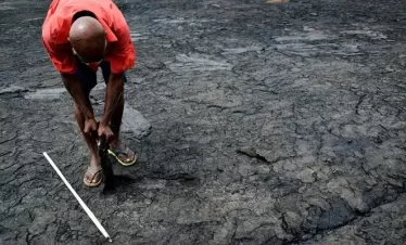 tour guide at pitch lake demonstrating different aspects of the pitch,