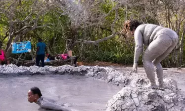 a lady getting ready to dive into a natural pool of volcani mud.