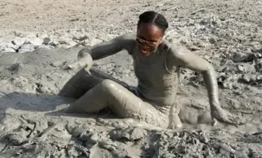 a lady playing in the mud after skating down a volcanic mud slope