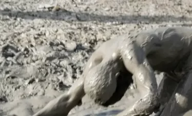 a man covered in volcanic mud