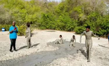 visitors taking pictures of people skating down a volcanic mud slope