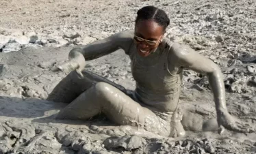 a lady playing in the mud after skating down a volcanic mud slope